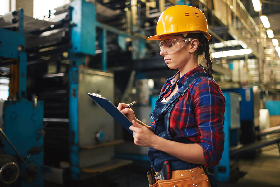 Young woman making notes in document in factory